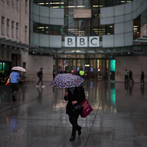 Mitarbeiter mit Regenschirmen vor dem Eingang der BBC-Redaktion 