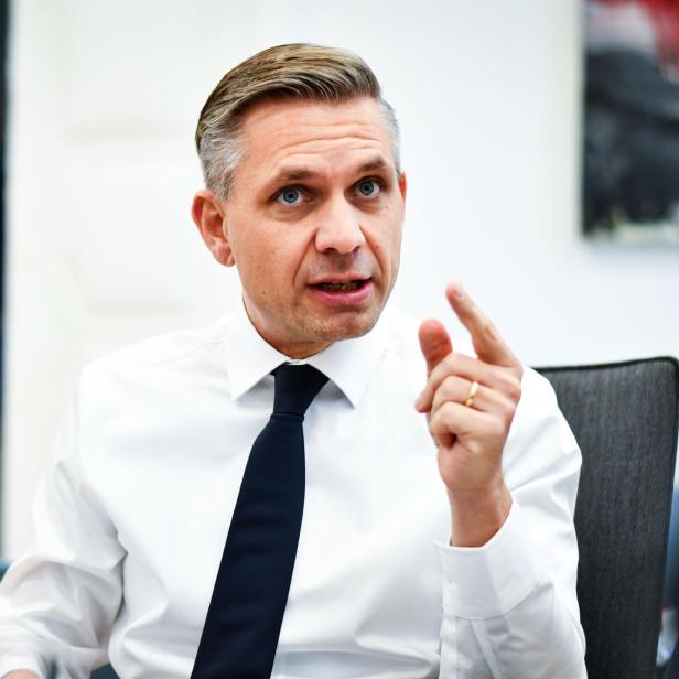 zu sehen ist der ÖVP-Wirtschaftsminister Wolfgang Hattmannsdorfer in einer Interviewsituation, er trägt ein weißes Hemd und Krawatte