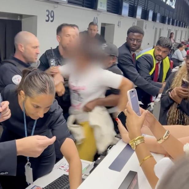 Eine schreiende Frau muss am Pariser Flughafen von der Security abgeführt werden.