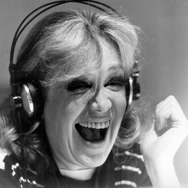 Hildegard Knef, lachend, mit Kopfhörern übergestülpt.