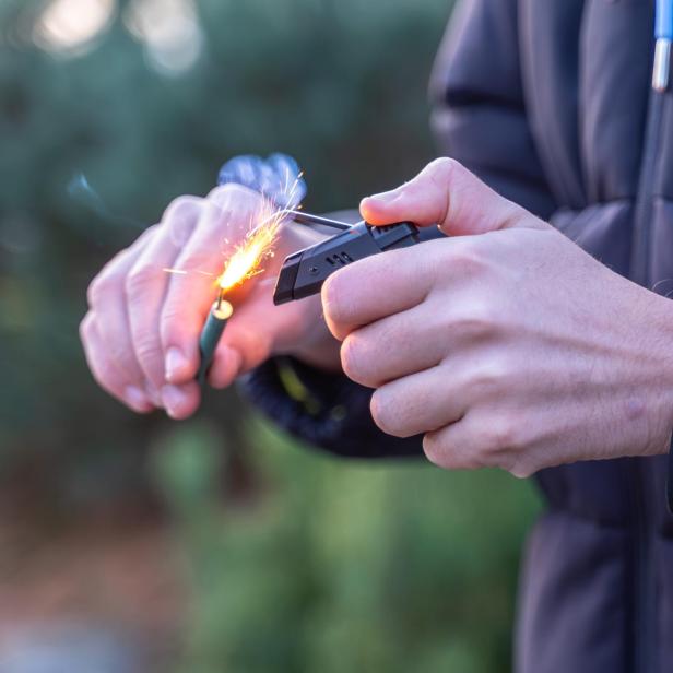 zu sehen ist ein Feuerwerkskörper, der in der Hand gezündet wird