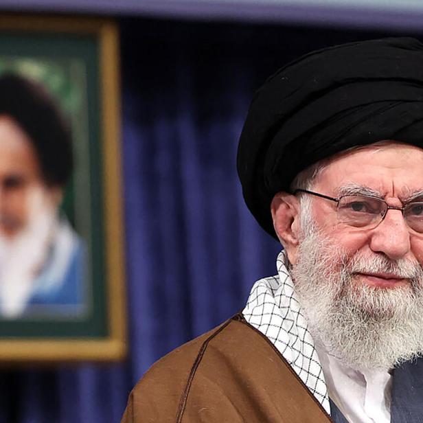 Irans oberster Führer Ayatollah Ali Khamenei steht vor einem Bild von Ruhollah Chomeini.