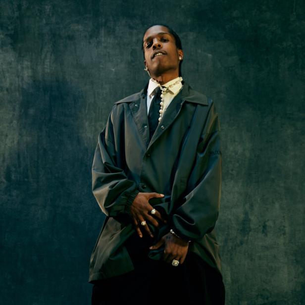 Rapper Asap Rocky posiert in grauem Anzug vor grauem Hintergrund