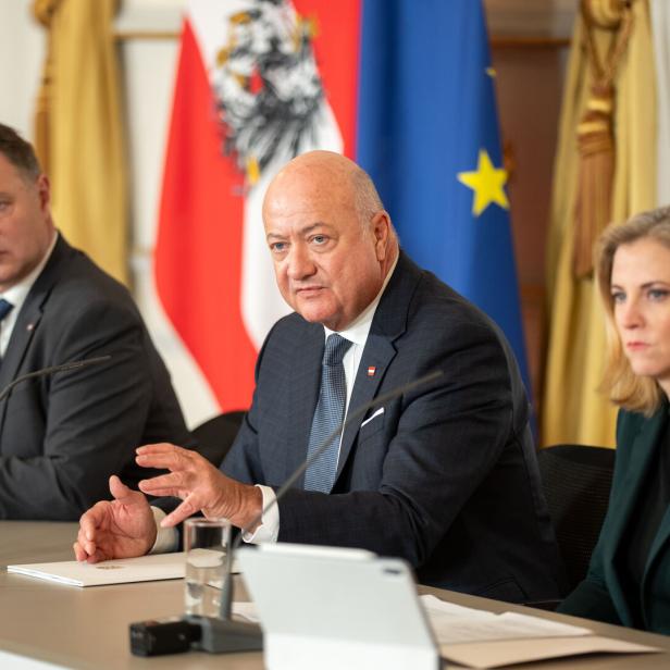 Drei Personen, es sind Stocker, Babler und Meinl-Reisinger, sitzen an einem Tisch vor österreichischen und EU-Flaggen.