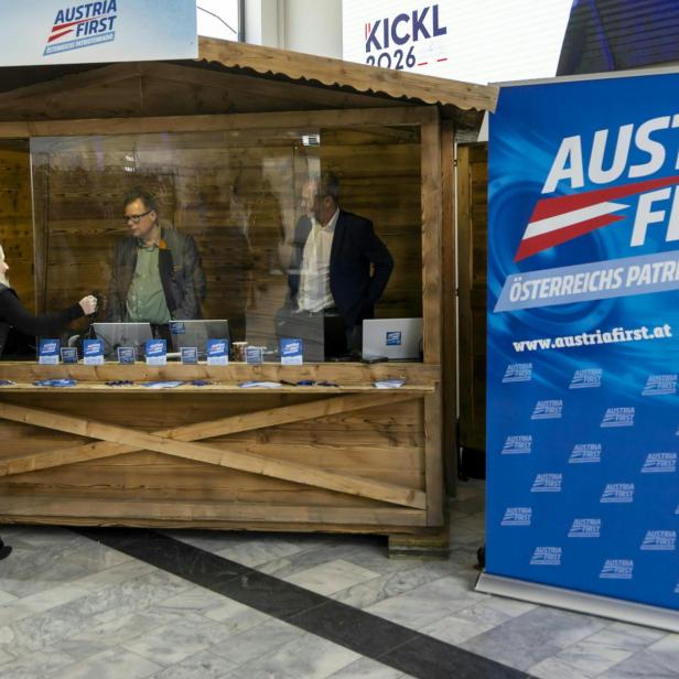 Der Stand des Senders Austria First beim Neujahrstreffen der FPÖ 2026 in Kärnten. Zu sehen sind zwei Personen in einer Hütte, hinter einer Glaswand.