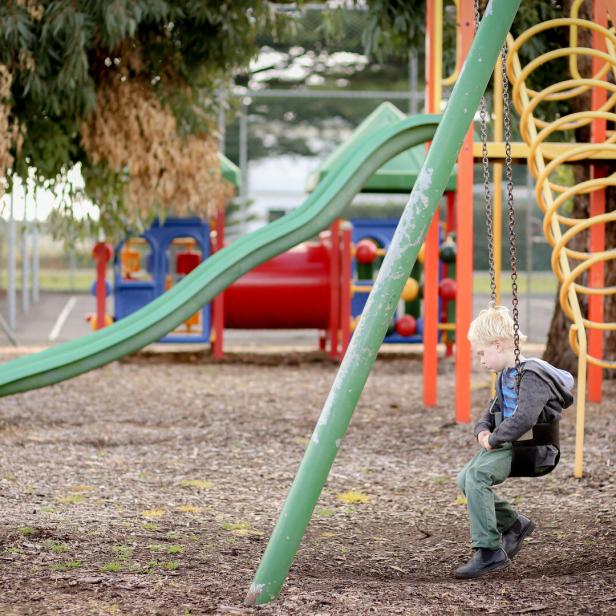 Ein Kind sitzt allein auf einer Schaukel am Spielplatz.
