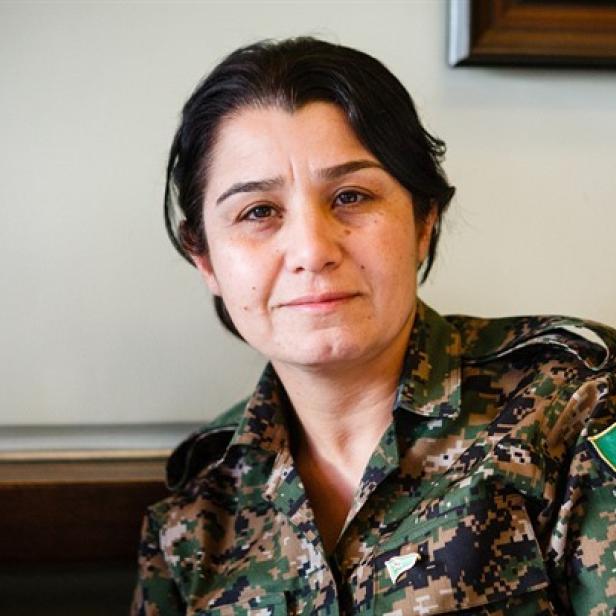 Nesrin Abdullah in Tarnkleidung, sie trägt am Arm einen Aufnäher mit der Aufschrift "YPJ" und einem roten Stern.