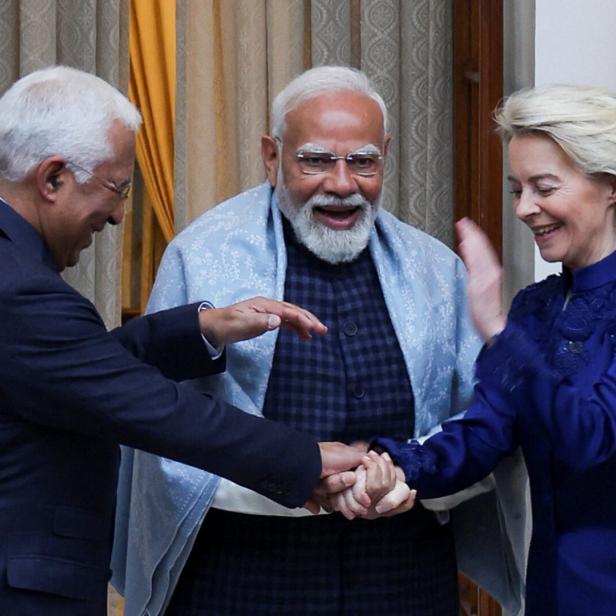 Eu-Kommissions Präsidentin von der Leyen (rechts) und Europäischer Rats Präsident António Costa (links) schütteln die Hände von Indiens Premier Narendra Modi (Mitte). Im Hintergrund rechts ist eine indische Fahne zu sehen.