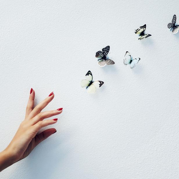 Schmetterlinge fliehen vor einer Hand, die sie zu fassen sucht 
