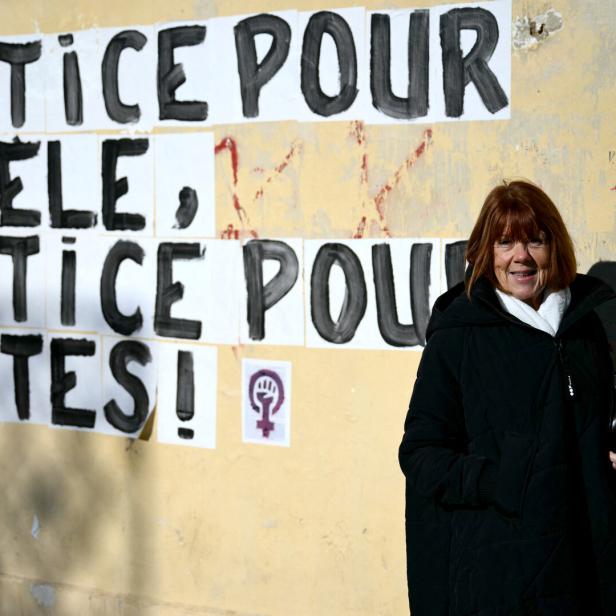Gisèle Pelicot steht vor einer Mauer, auf der geschrieben steht: „Gerechtigkeit für Gisèle, Gerechtigkeit für alle!