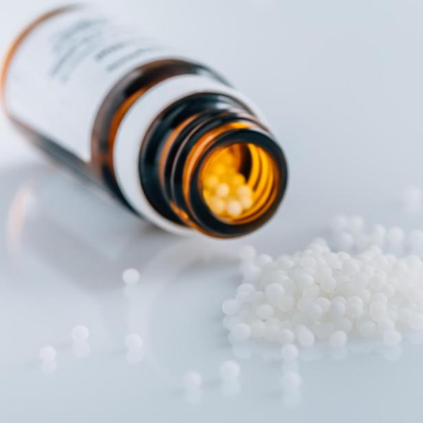 Ein Glasfläschchen, das homöopathische Globuli beinhaltet.
