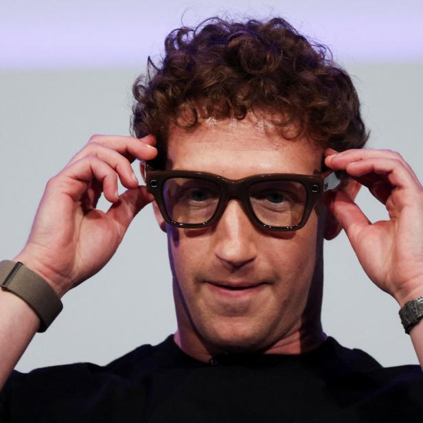 Mark Zuckerberg setzt eine braune Brille auf.