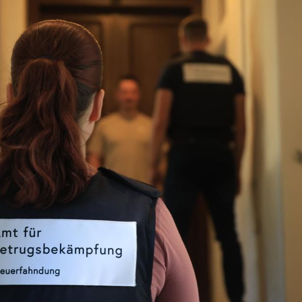 Steuerfahnder stehen vor einem Mann