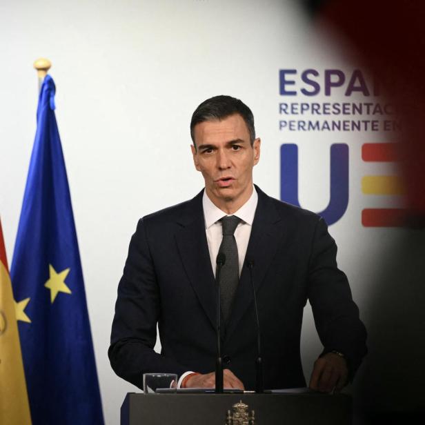 Pedro Sánchez steht vor einer Spanien- und EU-Flagge.