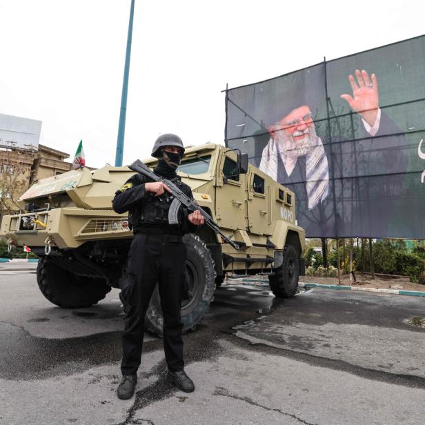 Ein vermummter Bewaffneter vor einem Militärjeep