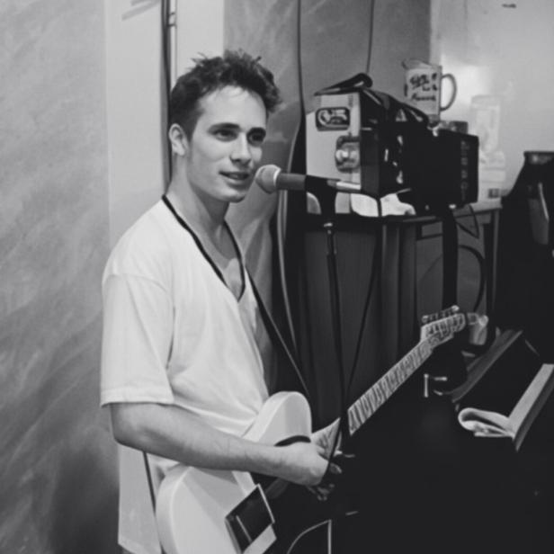 Schwarzweißes Foto des jungen Musikers Jeff Buckley in weißem T-Shirt an seiner Gitarre im Studio