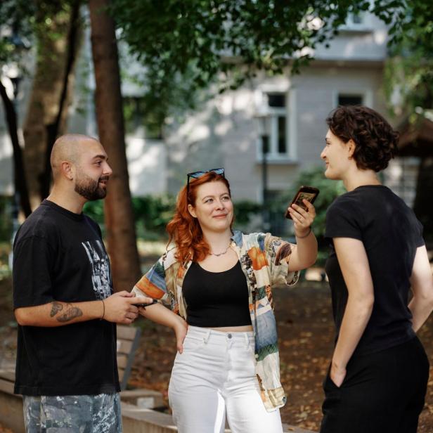 Ein Mann und eine Frau interviewen in einem Parkgelände eine weitere Person