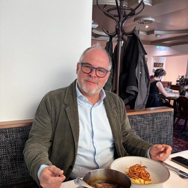 Hotelier Wolfgang Gröller sitzt an einem Wirtshaustisch, vor sich ein Kupferkessel und ein Teller mit Kartoffelpüree