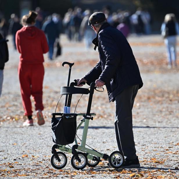 Ein Pensionist mit Rollator im Park.