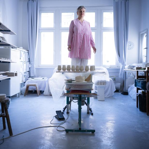 Die Künstlerin Uli Aigner steht in ihrem Studio auf einem Hocker