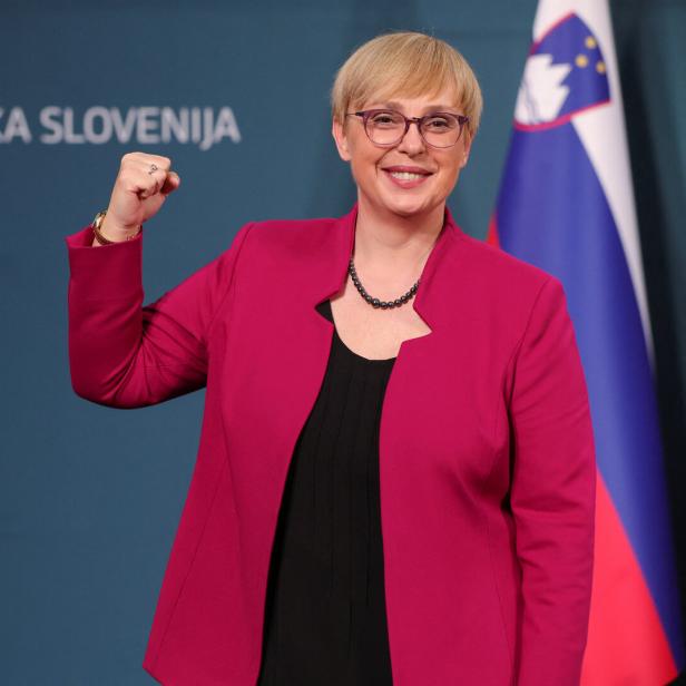 Eine Frau reckt vor der Flagge Sloweniens die Faust