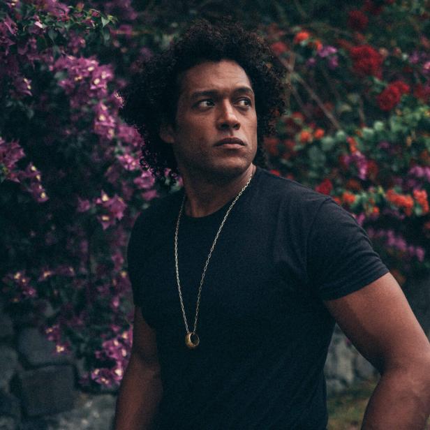 Der US-Musiker Makaya McCraven vor einer blühenden Staude