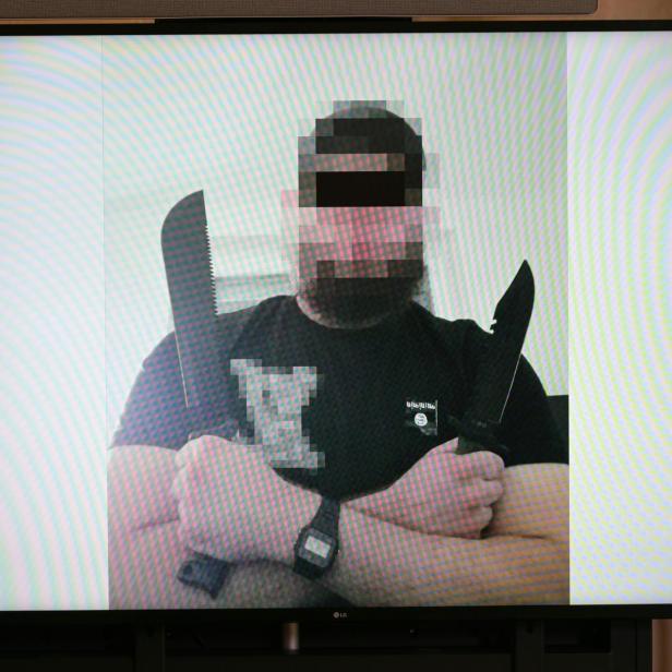 Mann mit verpixeltem Gesicht hält zwei große Messer vor weißem Hintergrund gekreuzt in den Händen.