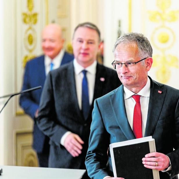 Finanzminister Markus Marterbauer geht in einen Raum, hinter ihm Vizekanzler unscharf Andreas Babler
