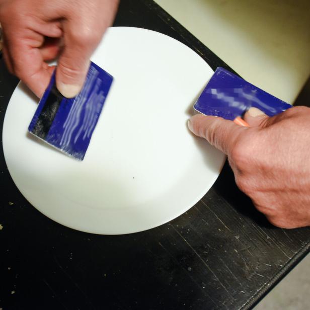Zu sehen sind zwei Hände, die mit Plastikkarten ein Rauschgift-Pulver portionieren