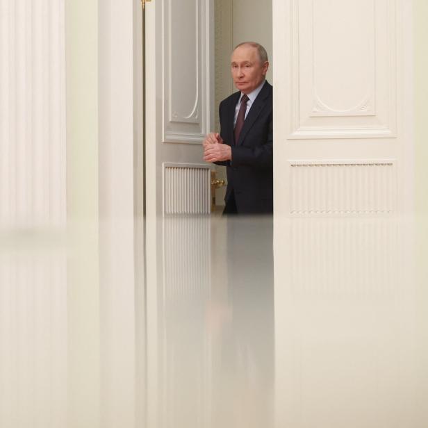 Putin betritt einen Raum durch eine weiße Tür