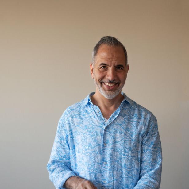Yotam Ottolenghi steht an einem Schneidbrett und filetiert Zitronen