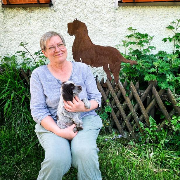 Die Patientin mit Welpen im Schoß im Garten