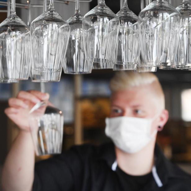 Barkeeper mit Maske hinter Weinkläsern