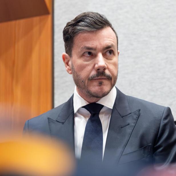 Mann in dunkelblauem Anzug vor hellem Hintergrund.