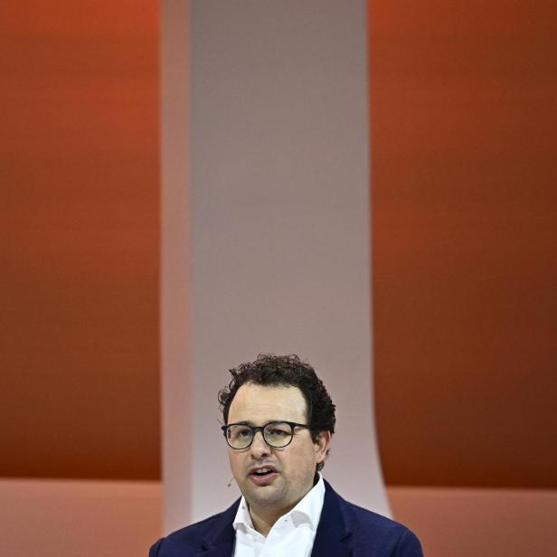 Dario Amodei spricht auf einer Bühne vor orangefarbenem Hintergrund.