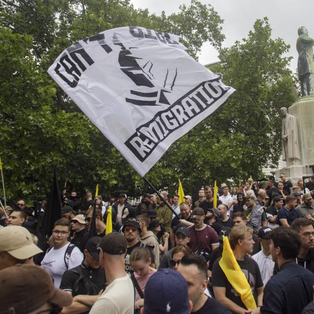 Menschenmenge bei einer Demonstration mit schwarzen und gelben Fahnen vor einem Denkmal.