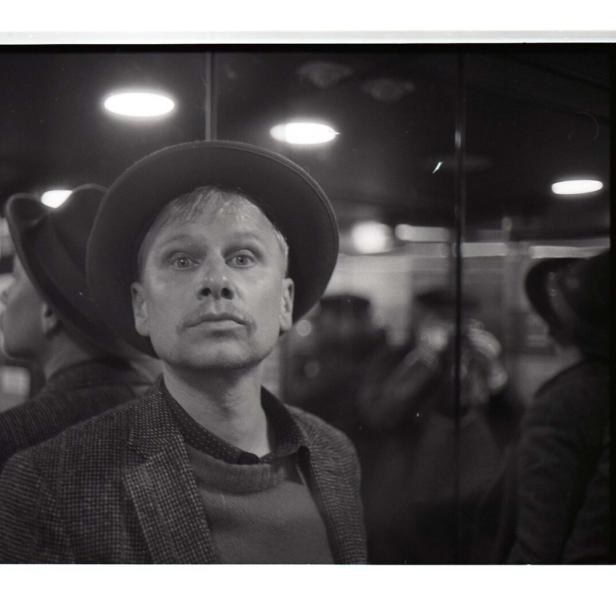 Der Schauspieler und Musiker Robert Stadlober mit Hut und erstauntem Blick in einem schwarzweißen Bild 