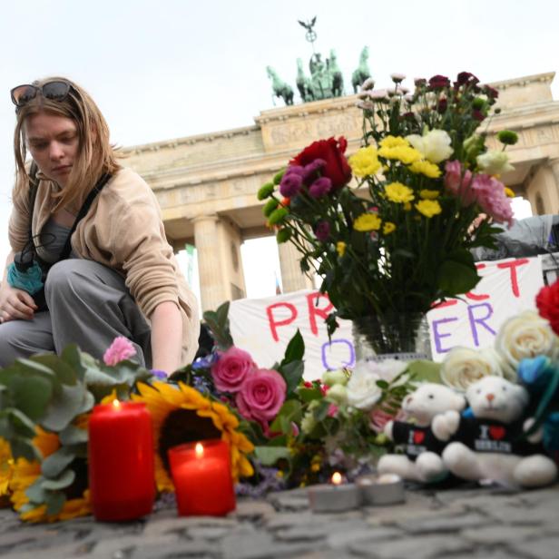 Eine trauernde Frau legt Blumen beim Brandenburger Tor ab.