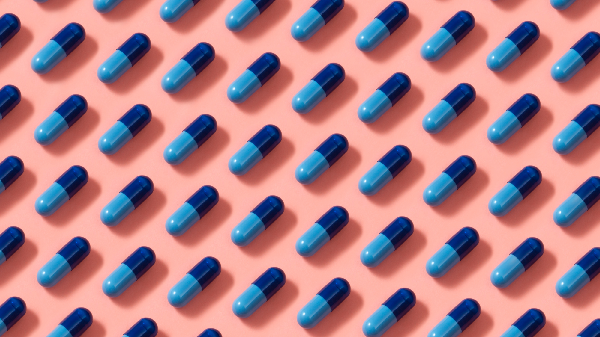 Mehrere blaue Pillen auf einem pinken Hintergrund