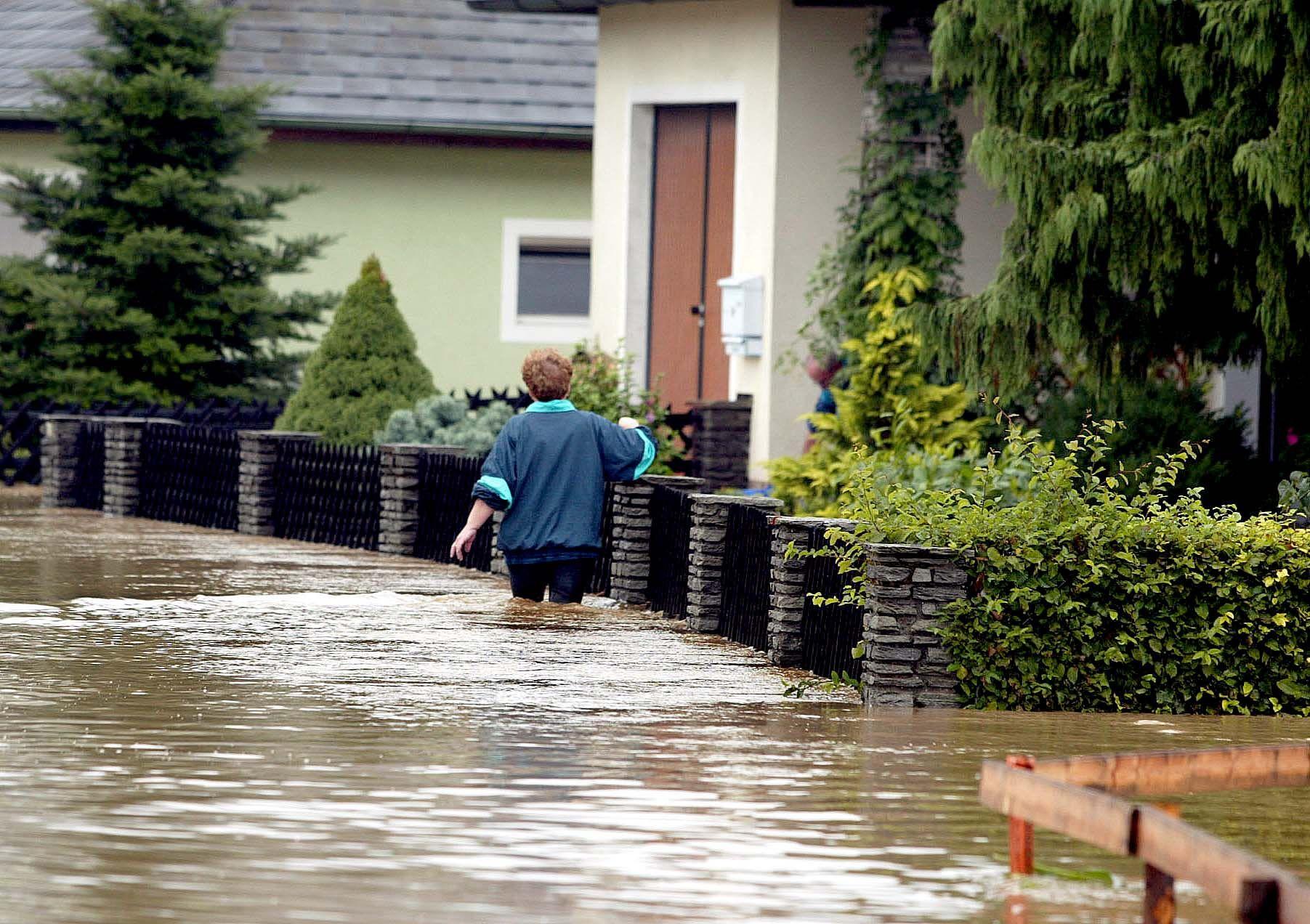 Eine Frau steht 2002 in Schwertberg bis zu den Oberschenkeln im Wasser vor ihrem Haus.