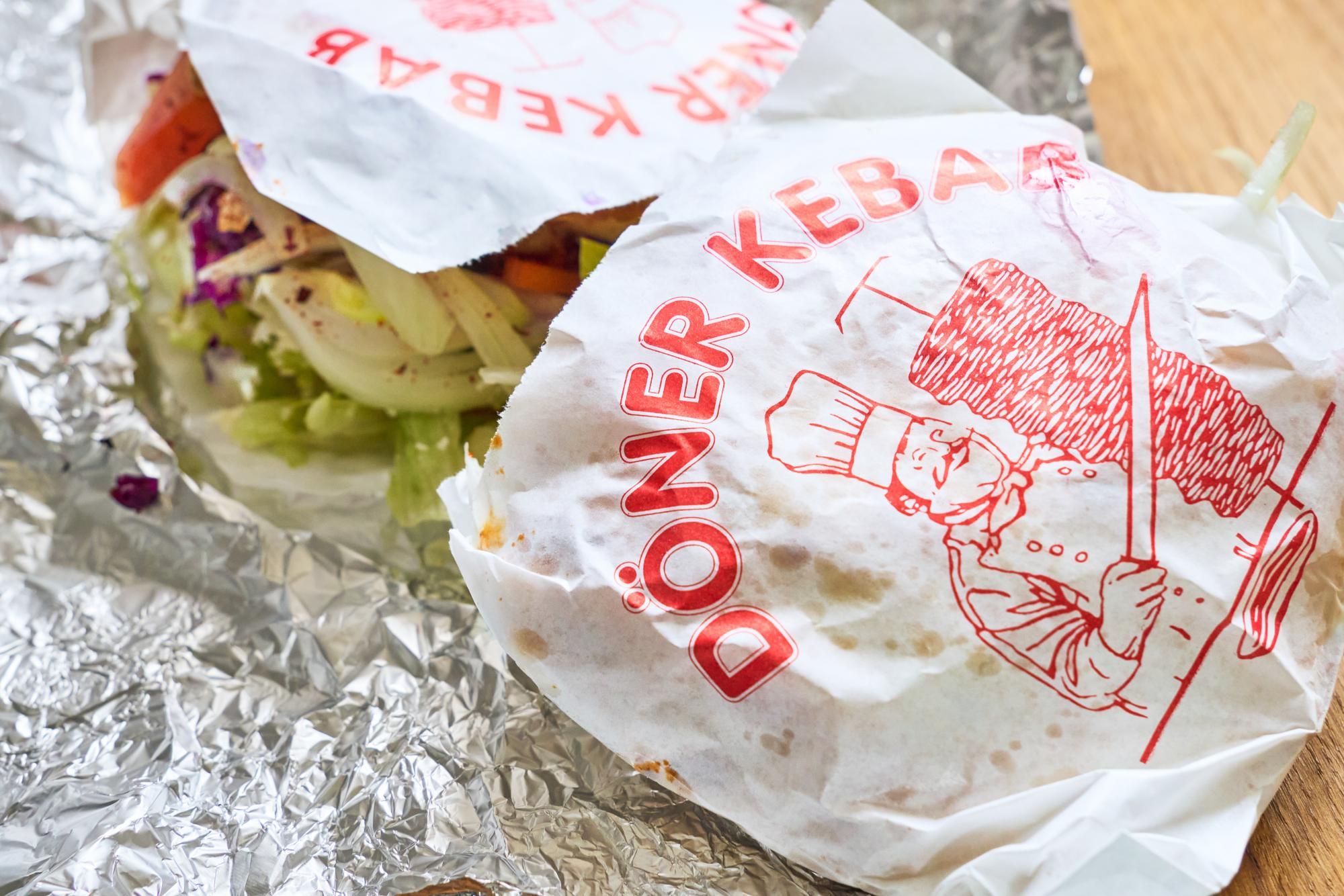 Ein frisch zubereiteter vegetarischer Döner Kebab, eingewickelt in Alufolie, zeigt leckeres Gemüse und frischen Salat, das in einem Fladenbrot verpackt ist